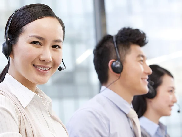 Three customer service representatives are smiling and wearing headsets.