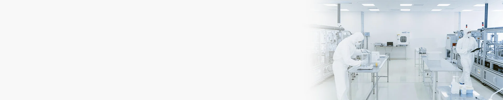 Two persons in protective clothing are working inside a cleanroom.