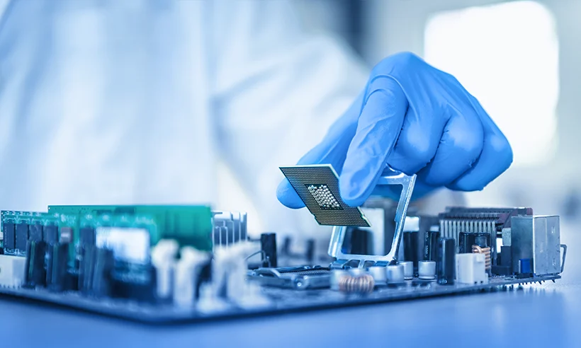 A technician in a protective suit is mounting an electronic component.