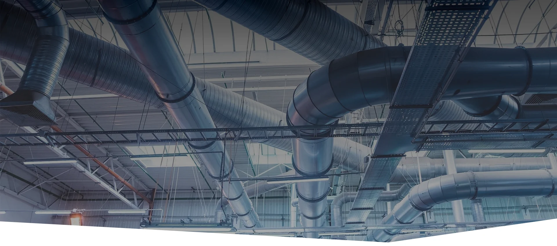 Ventilation ducts for air transport are interlaced across the ceiling of the factory.
